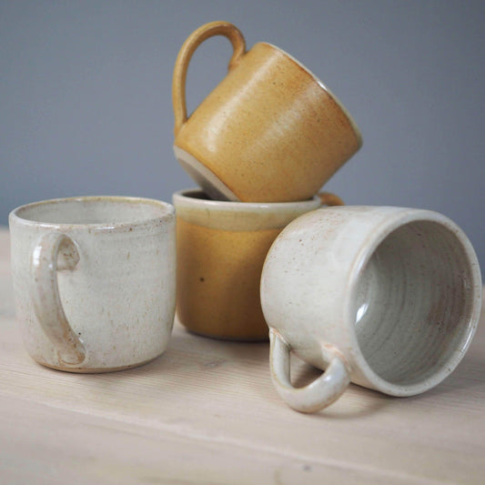 Collection of handmade coffee mugs in mustard and white 